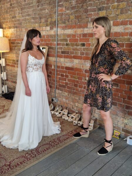 Sabrina from Love is Blind UK wearing her wedding dress with Caroline Black from Evelie in the changing room. 